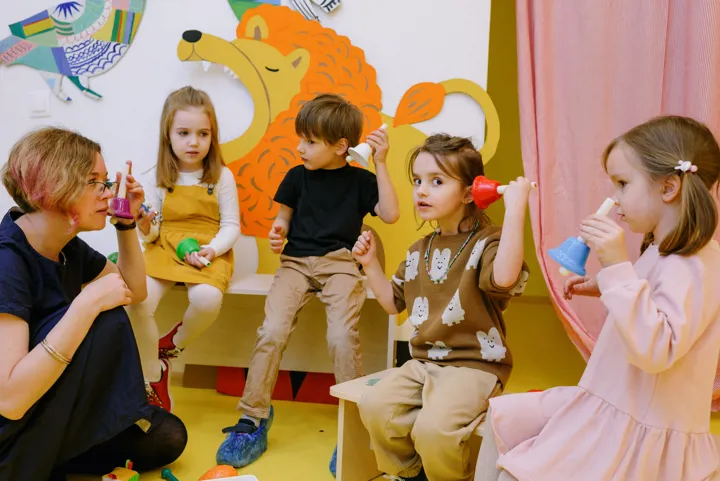 Éducatrice avec de jeunes enfants qui jouent avec des cloches