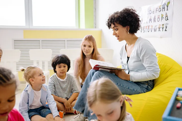 Éducatrice qui lit un livre à de jeunes enfants