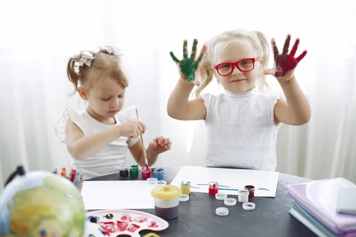 Jeunes filles qui peinturent avec leurs mains à une table
