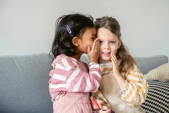 Jeune fille qui parle dans l'oreille de son amie